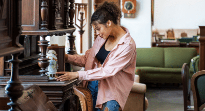 A woman looks at an antique tin container while at an estate sale.