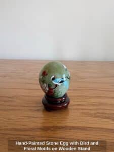Hand-Painted-Stone-Egg-with-Bird-and-Floral-Motifs-on-Wooden-Stand