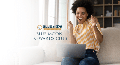 A woman celebrates signing up on her computer for the Blue Moon Rewards Club, representing estate sales shopping community.