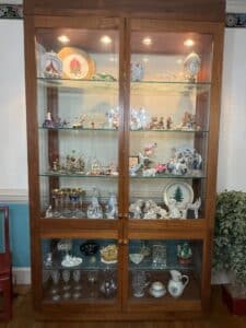Collection-of-Decorative-Porcelain-Figurines-and-Glassware-in-a-Lighted-Wooden-Curio-Cabinet