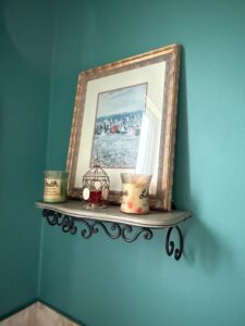 Distressed-Gray-Scrollwork-Shelf-with-Faith-and-Love-Candles-and-Beach-Scene-Print