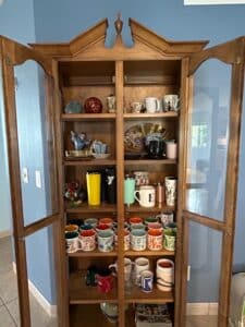 Wooden-Curio-Cabinet-with-Assorted-Mugs-and-Decorative-Items