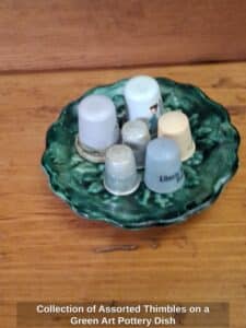 Collection-of-Assorted-Thimbles-on-a-Green-Art-Pottery-Dish