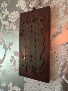 Vintage-Wooden-Cribbage-Board-with-Ornate-Brass-Overlay-and-Decorative-Cutouts-second-image