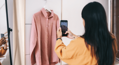 A woman takes a photo of a shirt to post for the estate sale today.