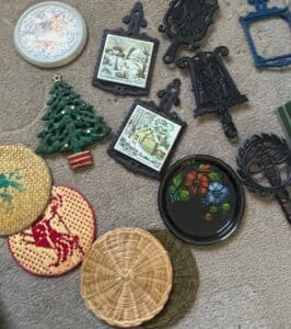 Vintage-Cast-Iron-Trivets-with-Scenic-Inserts-Ceramic-Christmas-Tree-Enameled-Tray-and-Woven-Coasters