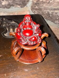 Red-Laughing-Buddha-Figurine-on-Wooden-Stand