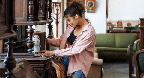A woman looks at an antique tin container while at an estate sale.