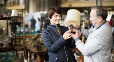 A man and woman examine a wooden duck at an estate sale.